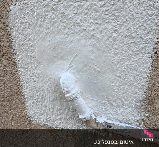 צינור צבוע בלבן על קיר מחוספס